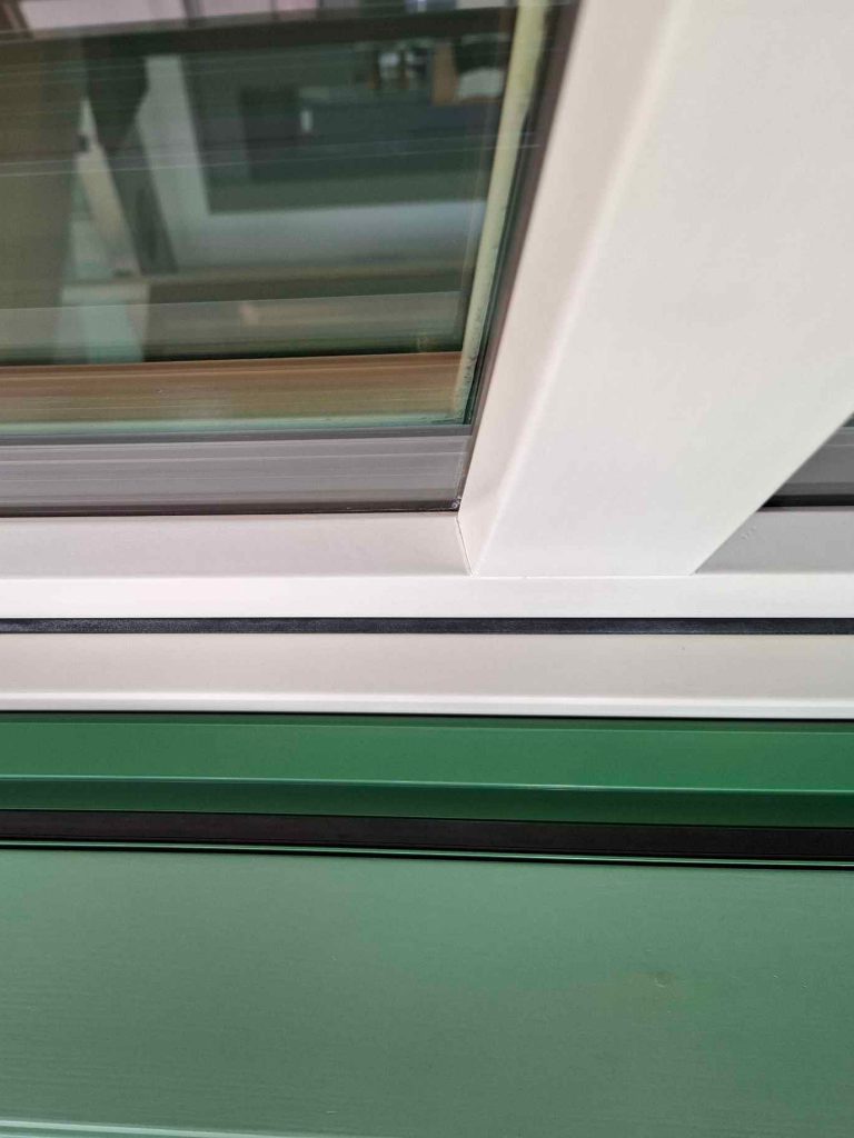 Angolo di un serramento in legno verniciato verde con il fermavetro inclinato