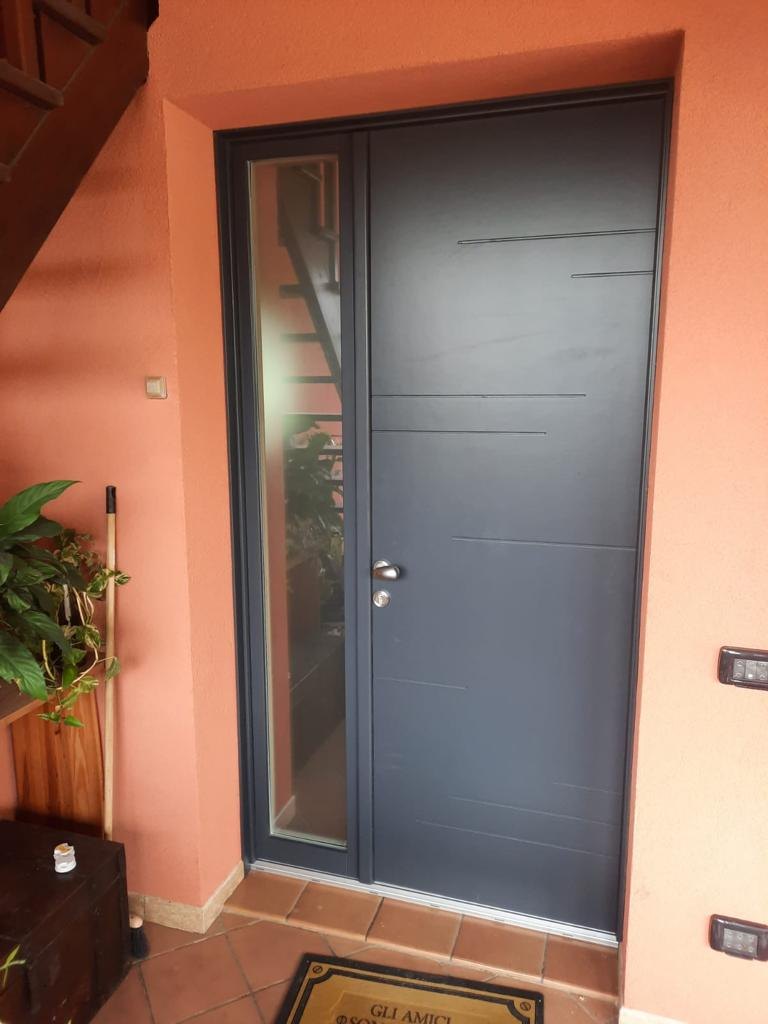 Portoncino d’ingresso grigio con fresature orizzontali e vetro laterale